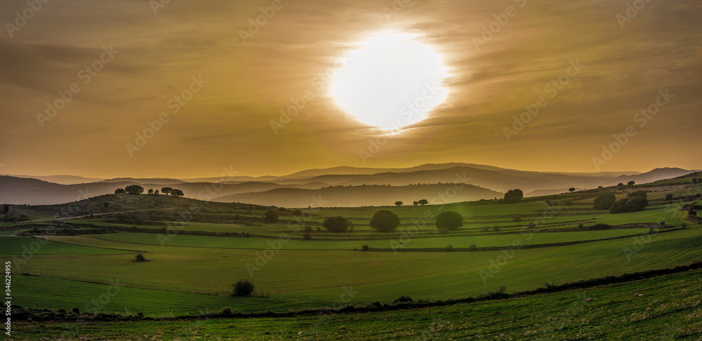 sunset panorama in the cereal fields view of valleys and mountains, warm colours and oranges, blues