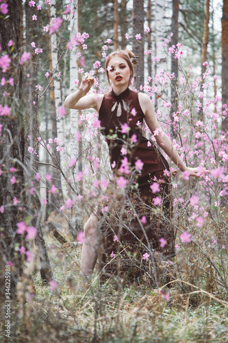 A girl dressed in Japanese style in a flowering forest among pink flowers