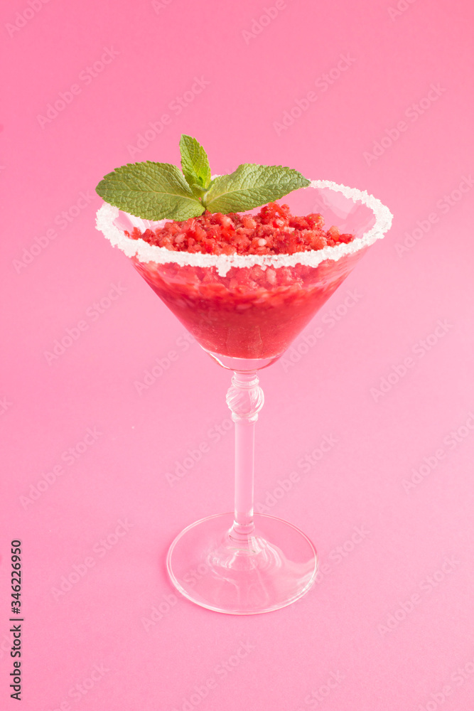Frozen juice with strawberry in a one martini glass on the pink background. Location vertical. Closeup. Frozen juice with strawberry in a one martini glass on the pink background. Location vertical. Closeup.