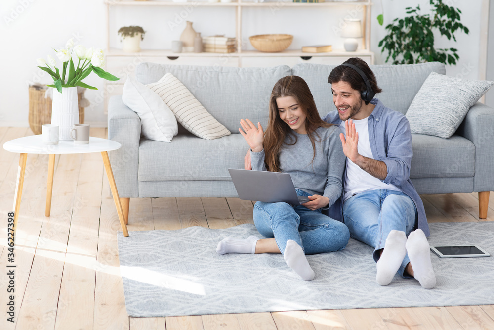 Cheery young couple having video call with friends