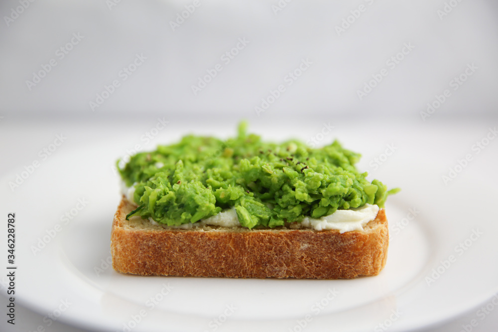 Classic English pea and ricotta toast on white plate