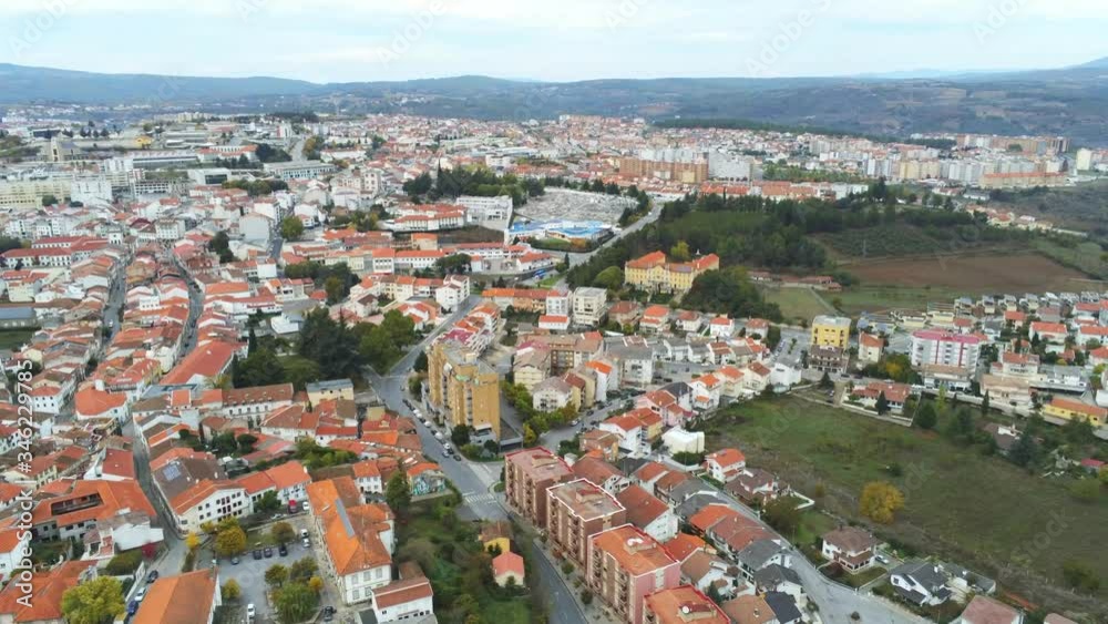 Aerial shot of quiet city with orange rooftops at dawn, surrounded by hills Aerial shot of quiet city with orange rooftops at dawn, surrounded by hills