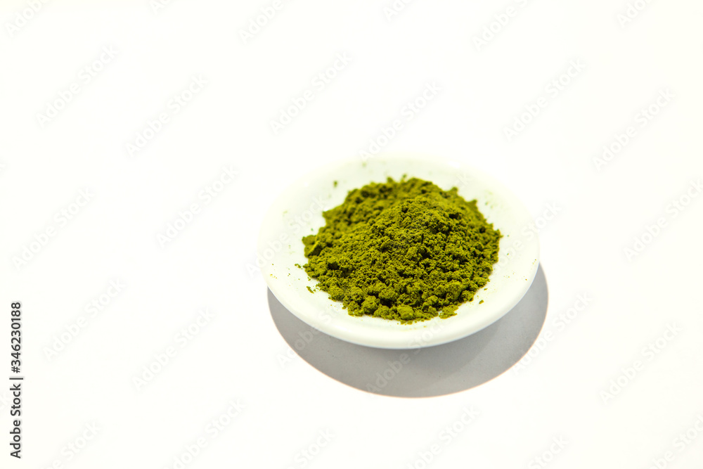 Green powder of Japanese matcha tea on a platter, isolated on a white background. Loose powder Green powder of Japanese matcha tea on a platter, isolated on a white background. Loose powder