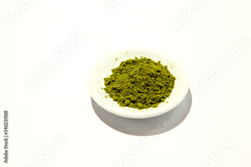 Green powder of Japanese matcha tea on a platter, isolated on a white background. Loose powder