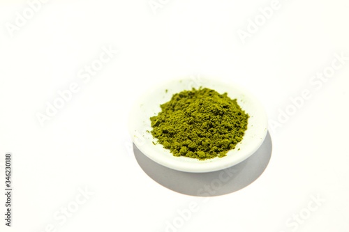 Green powder of Japanese matcha tea on a platter  isolated on a white background. Loose powder