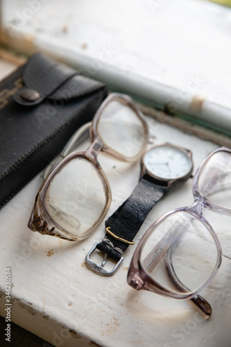 Old glasses and retro watch on white background near window