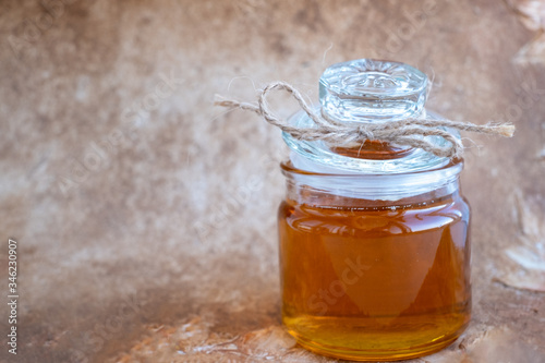 Fresh honey on a glass container on a beige background.