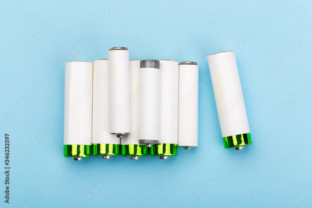 many new and used batteries of different shapes, AA, round batteries on a blue background. many new and used batteries of different shapes, AA, round batteries on a blue background.