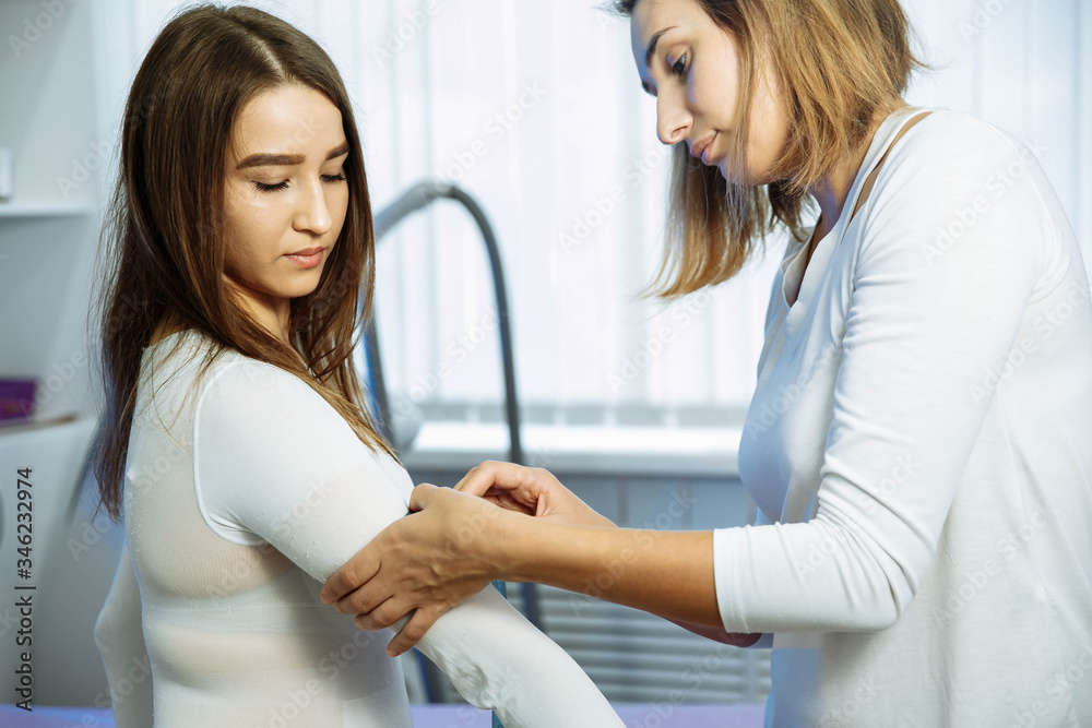 Specialist measuring waist. Dark-haired young qualified massage specialist measuring waist of client. LPG massage Specialist measuring waist. Dark-haired young qualified massage specialist measuring waist of client. LPG massage