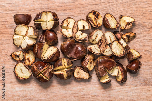 Roasted chestnuts scattered on a wooden surface with a view from above, edible delicious chestnut