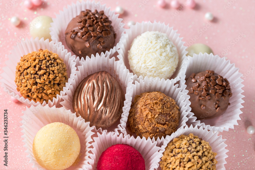 Cute chocolate candies with sugar decorations on a pink shiny background Cute chocolate candies with sugar decorations on a pink shiny background