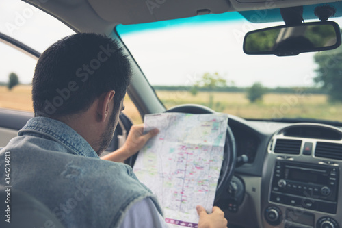 A man sits in a car and looks at a map of the area.