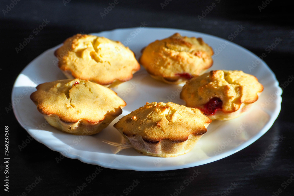 gluten-free redcurrant cupcakes sit on a round white plate on a dark table . gluten-free food and diet . prepared at home gluten-free redcurrant cupcakes sit on a round white plate on a dark table . gluten-free food and diet . prepared at home