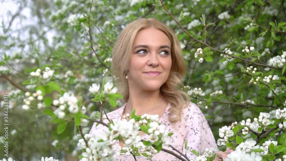 CloseUp Beauty young woman enjoying nature in spring flowering trees. Happy girl in Garden with flowers. Beautiful blonde girl posing in blooming tree branches with white flowers. Follow the focus CloseUp Beauty young woman enjoying nature in spring flowering trees. Happy girl in Garden with flowers. Beautiful blonde girl posing in blooming tree branches with white flowers. Follow the focus