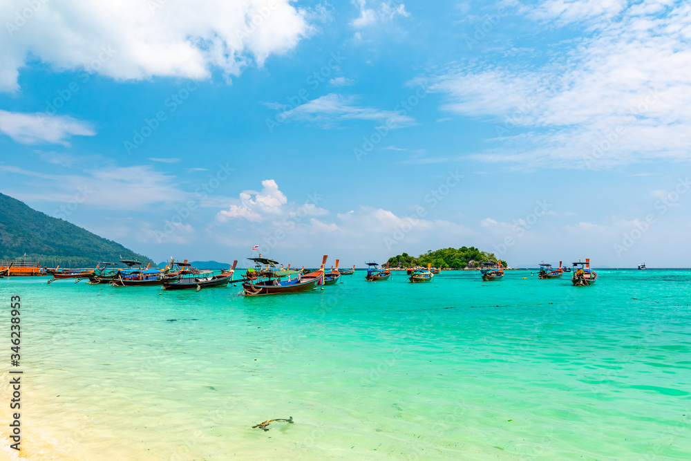 Obraz premium Long tail boats in small harbor at Ko Lipe island, south Thailand. Tropic and exotic island is symbol of tropical paradise, part of Tarutao national nature park. Vibrant colors, turquoise water.