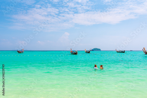 Two unidentifiable girls are snorkeling at Ko Lipe island, Thailand. Turquoise sea, pure water and coral reef with many tropical and exotic animals.