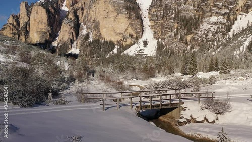 Aerial view of the valley in Fannes-Sennes natural park. Snow covering valley floor and the forest. Shallow river meandering through the valley. A narrow bridge above the river. photo