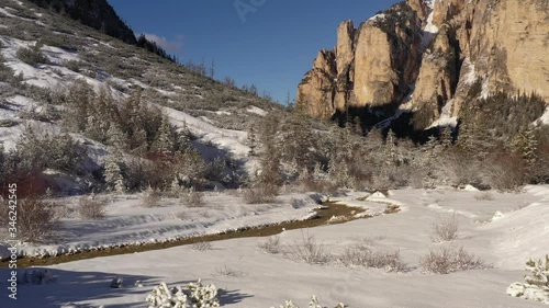 Aerial view of the valley in Fannes-Sennes natural park. Snow covering valley floor and the forest. Shallow river meandering through the valley. Mountains tower on the sides. photo