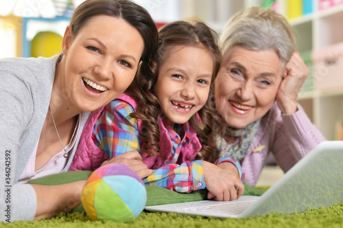 Portrait of happy family with laptop lying on floor at home