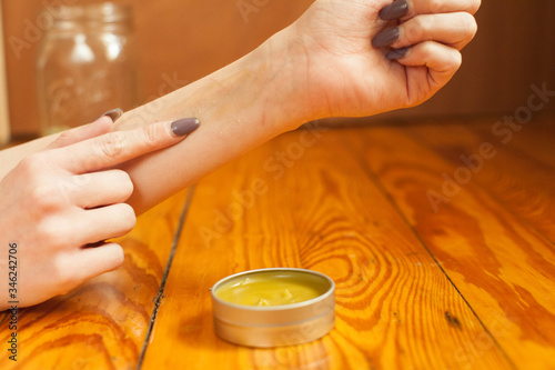 Female lady with nice finger nails rubbing massaging all natural organic home made self care cannabis CBD balm from tin with great natural weed smell to body skin muscle ache hand pain relief 