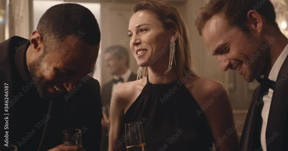 Group of friends having a discussion over a few drinks and meeting a couple at party. Multi-ethnic people are laughing and having a good time together at a party.
