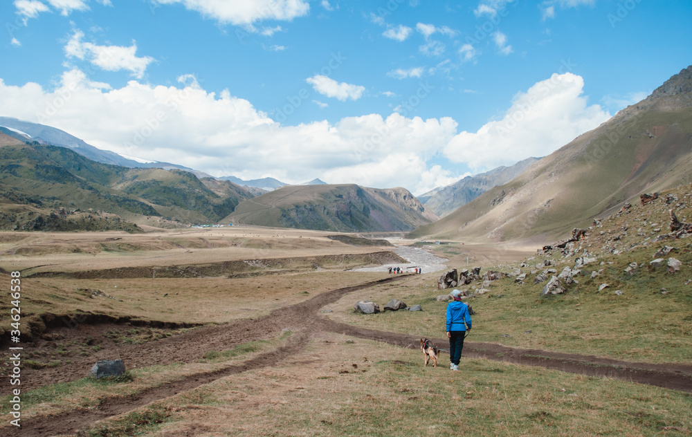 A girl walks with a dog in the mountains. Girl and German shepherd, Elbrus national Park.