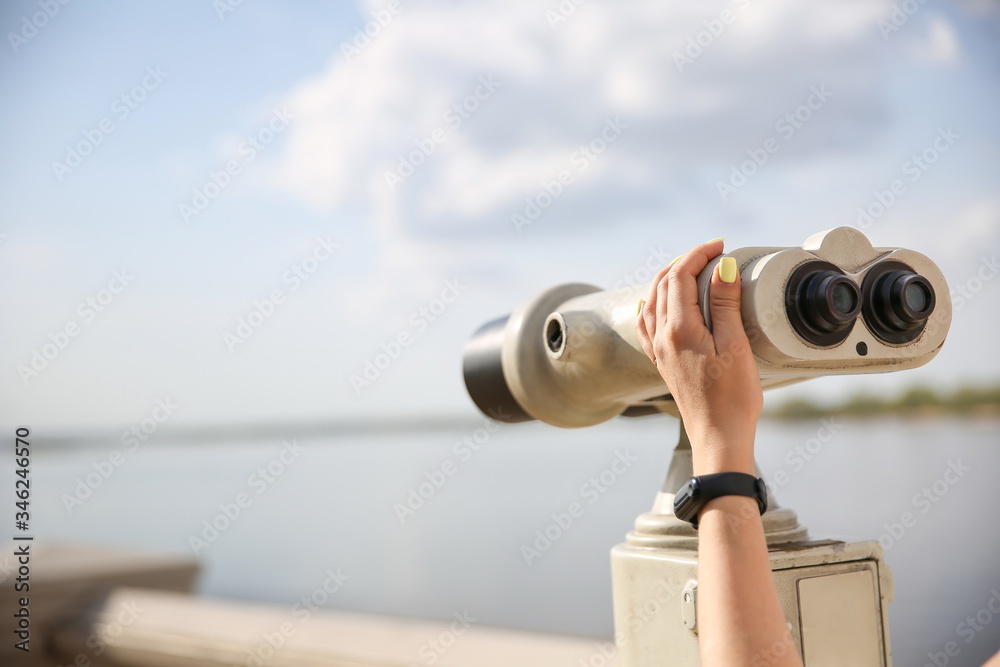 woman's hand holding observation binocular against skyline close up with copy space