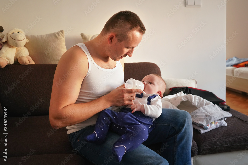 Young man feeding milk his baby boy son from bottle