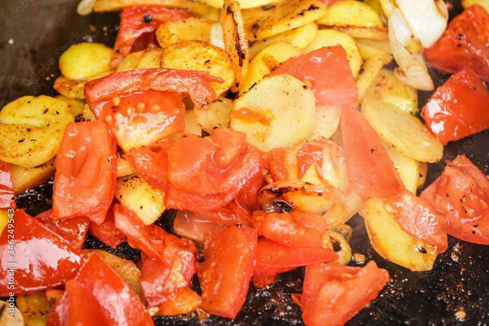 Potatoes and tomatoes cut to small pieces grilled on electric grill, closeup detail Potatoes and tomatoes cut to small pieces grilled on electric grill, closeup detail