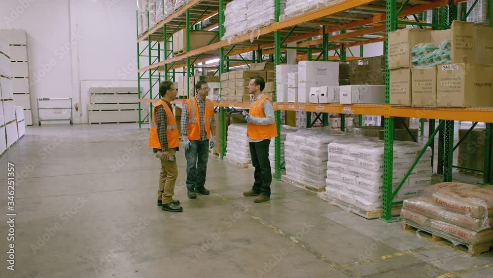 WS DS TS Three workers walking and talking in Warehouse, Drywall with one holding tablet WS DS TS Three workers walking and talking in Warehouse, Drywall with one holding tablet