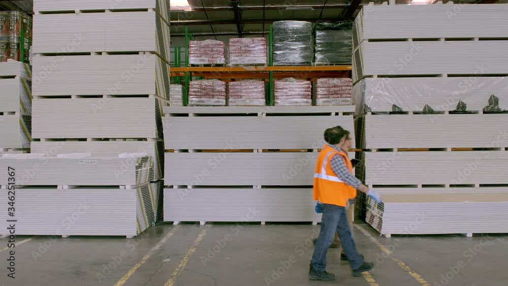 WS Three workers walking along stacks of goods in Warehouse, Drywall WS Three workers walking along stacks of goods in Warehouse, Drywall