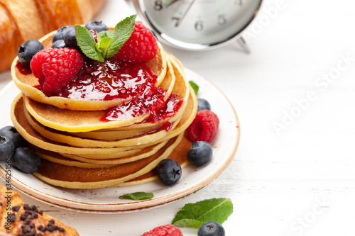 Delicious pancakes with berries and jam, croissants and coffee