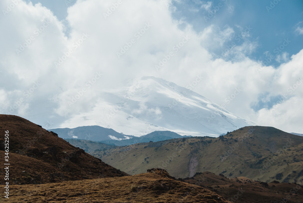 Beautiful Elbrus hid in the clouds. Cloudy weather in the mountains, sleeping volcano, snow in the mountains.