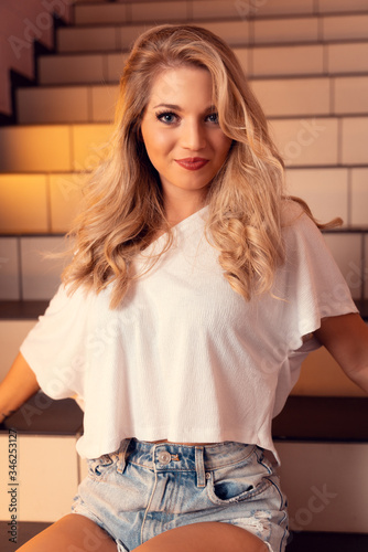 Blonde Sexy junge Frau in Jeans mit locken. Portrairt mit dezentem Licht und Schatten photo