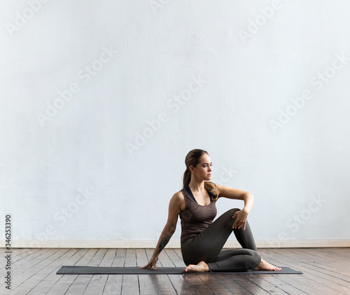 Young and fit woman practicing yoga indoor in the class. Stretching exercise in the day light. Sport, fitness, health care and lifestyle.