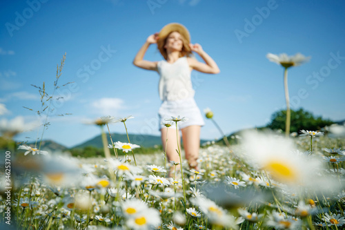 Woman in a field with flowers  bokeh effect. Beautiful woman runs across the field with daisies. 