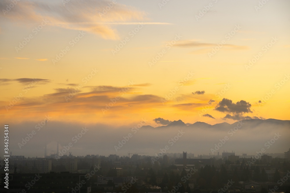 Sunrise and sunset, beautiful clouds over the meadow, hills and buildings in the town. Slovakia