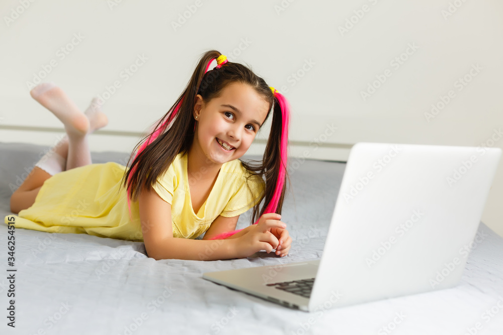 Cool online school. Kid studying online at home using a laptop. Cheerful young little girl using laptop computer studying through online e-learning system. Distance or remote learning Cool online school. Kid studying online at home using a laptop. Cheerful young little girl using laptop computer studying through online e-learning system. Distance or remote learning