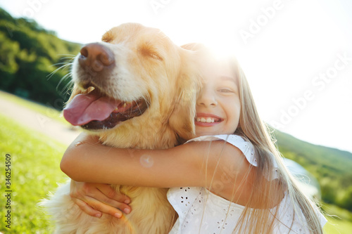 A child with a dog in nature. girl playing with a dog on green grass at sunset time.