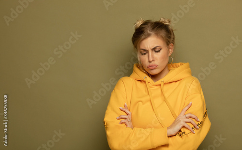 Unhappy depressed cute young woman in yellow pullover, frowning her face over green background. Female thinking about difficult situation in her life.