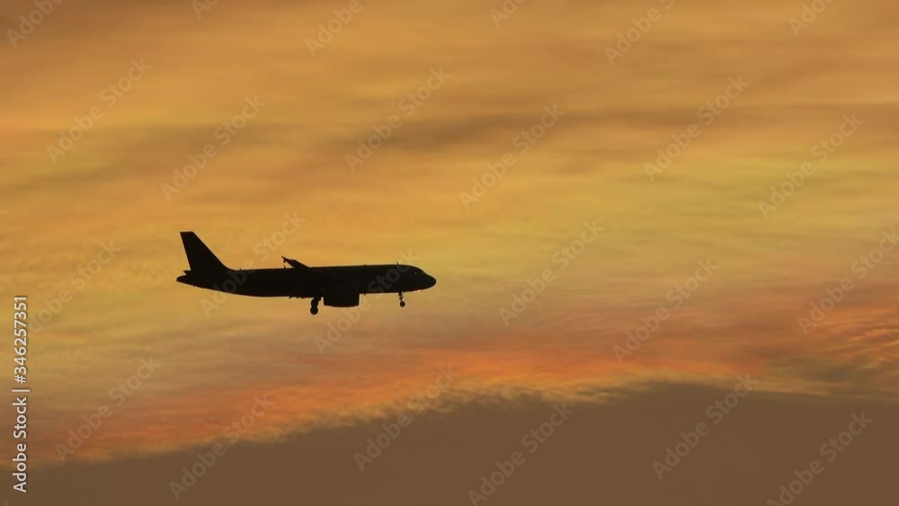 Silhoutte of plane flying over sunset sky background