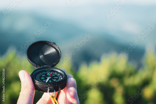 Hand holding compass on summer mountains background