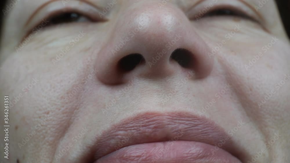 Macro shot of a displeased female face sniffing an unpleasant odor.