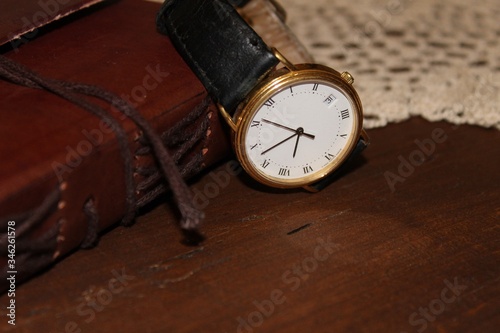 old wristwatch with leather notebook on old wooden chest with blanket