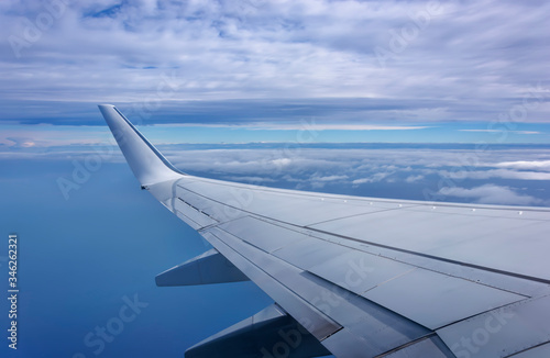 Aerial view of plane window above clouds under blue sky. View from aircraft window. Airline, business photo
