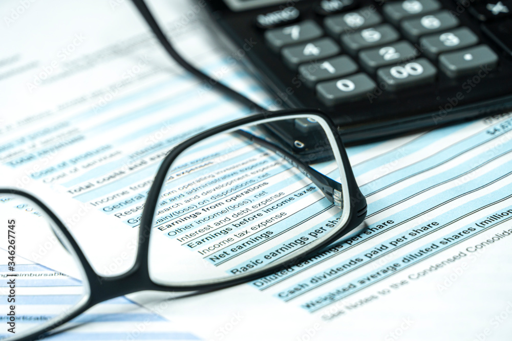 Fountain pen and eyeglasses on a quarterly corporate financial report. Income statement financial report through glasses. Investment analysis in financial crisis time. Fountain pen and eyeglasses on a quarterly corporate financial report. Income statement financial report through glasses. Investment analysis in financial crisis time.