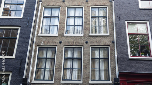 Looking up at the typical facade of houses with large traditional windows at old street of Amsterdam. Close up