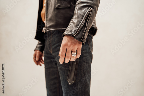 Close-up photo of the male hand with two rings and leather coat