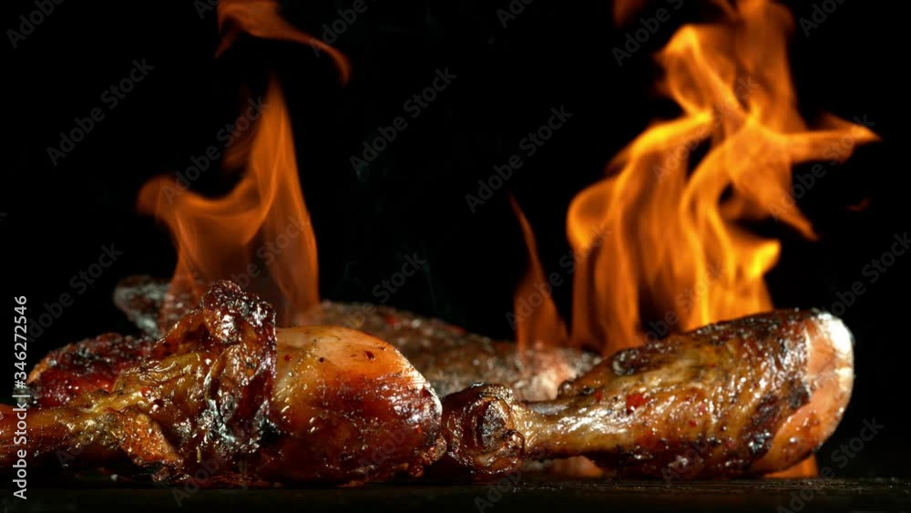 Super slow motion of chicken legs on grill with fire, on black background. Filmed on high speed cinema camera, 1000 fps Super slow motion of chicken legs on grill with fire, on black background. Filmed on high speed cinema camera, 1000 fps