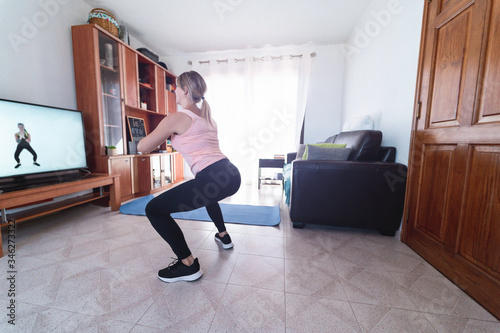 Young woman doing sport fitness at home while watching video tutorial on web app - Girl having workout online lesson during isolation quarantine - Healthy lifestyle concept - Focus on left foot